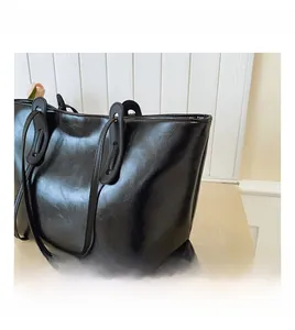 Detail shot of the glossy black faux leather texture and minimalist shoulder strap design