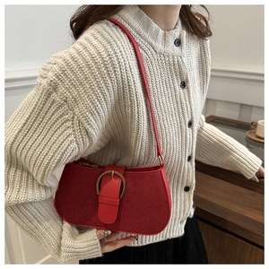 Detail of red vintage underarm bag featuring suede patchwork and antique brass hardware