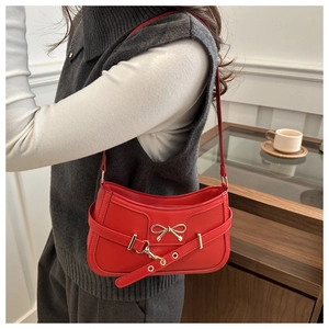 Detail der roten Leder-Schultertasche mit goldener Schleife an einem weiblichen Model