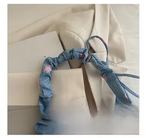 Detail of floral print denim crescent bag featuring a ruched cloud-style handle and zipper