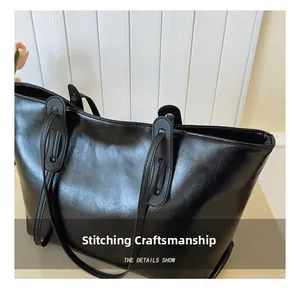 Detailed view of reinforced stitching and glossy leather texture on a black tote bag