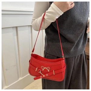 Détail du sac rouge en cuir avec un nœud en métal doré et une boucle de ceinture chic