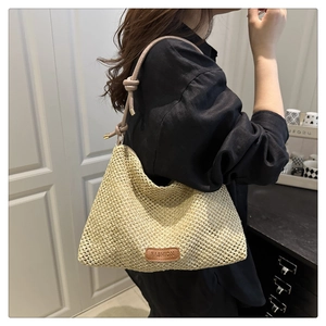Detail of woven straw tote bag with pink leather knotted strap and embossed fashion label