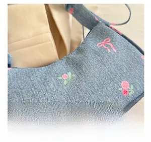 Close-up of blue denim shoulder bag with pink floral and bow print textures