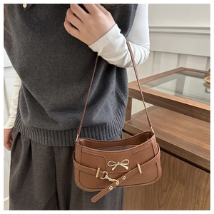 Detail einer braunen Vintage-Schultertasche mit goldener Schleife und dekorativem Gürtel