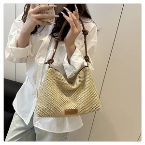 Detail of hand-woven straw tote with leather knotted strap and fashion tag detail