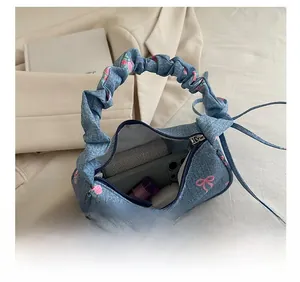 Detail showing internal capacity of blue denim handbag with floral bow and zipper