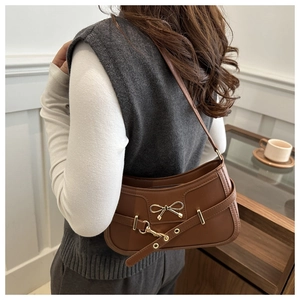 Gros plan sur un sac à bandoulière vintage marron avec nœud doré et boucle métallique
