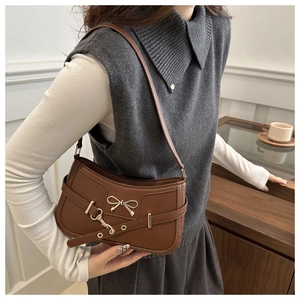 Detailed view of brown retro baguette bag with gold bow hardware and leather strap