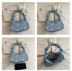 Detail of denim shoulder bag with pink floral embroidery and ruched handle detail