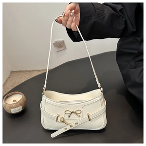 Detail der weißen PU-Schultertasche mit goldener Metallschleife und dekorativem Ösenriemen