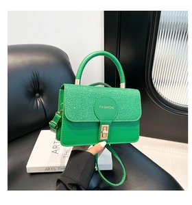 Detail of green leather handbag with glitter flap and golden rectangular twist lock