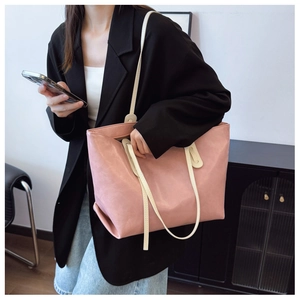 Side view of large pink leather tote bag with white shoulder strap on female model