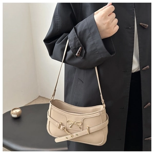 Détail du sac porté épaule abricot avec nœud doré et ceinture décorative à œillets