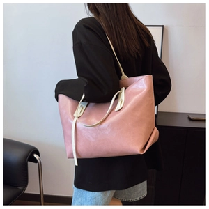Pink large tote bag with cream straps shown on model in a modern professional setting