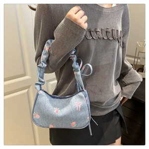 Detail of light blue floral handbag with pleated straps and pink rose patterns