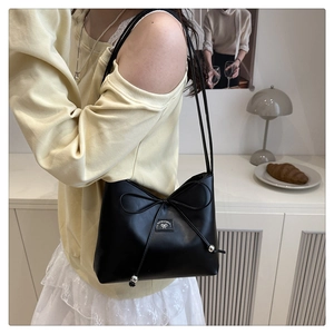 Dettaglio borsa a tracolla in pelle nera con elegante fiocco a coulisse e sfere in metallo
