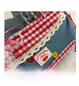Detail of sweet cherry embroidery and lace trim on denim patchwork handbag