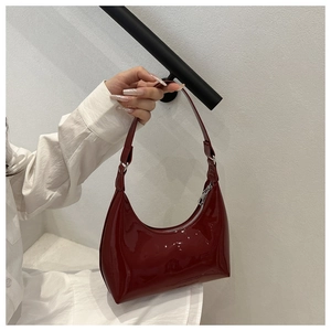 Detailed close-up of glossy burgundy patent leather shoulder bag with silver zipper