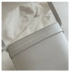 Close-up of reinforced double-stitched craftsmanship on a cream leather bucket bag