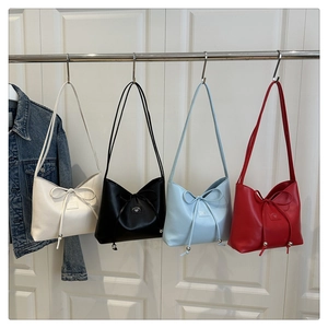 Detailansicht schicker Damen-Beuteltaschen in vier Farben mit Schleife und Metallkugeln