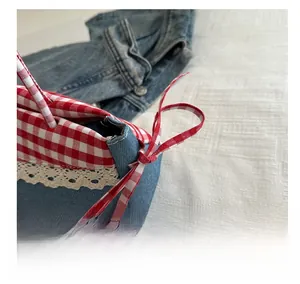 Detailed shot of blue denim bag with red checkered trim and crochet lace accents