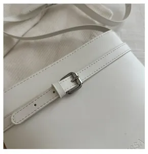 Close-up of white leather bucket bag with metallic buckle detail and embossed SSA logo