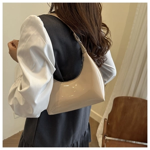 Detail of glossy cream white hobo bag showing the shiny patent leather finish and strap