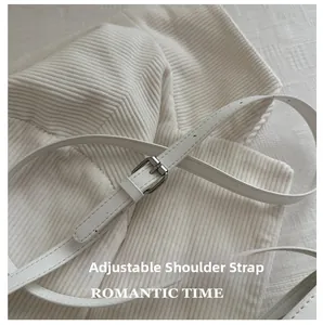 Close-up of adjustable white leather shoulder strap with silver buckle on corduroy