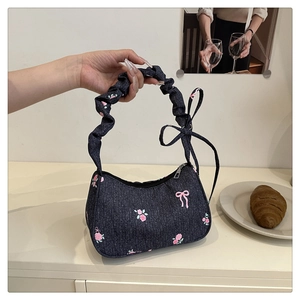 Detail of blue denim handbag with pink rose prints and pleated ruched handle
