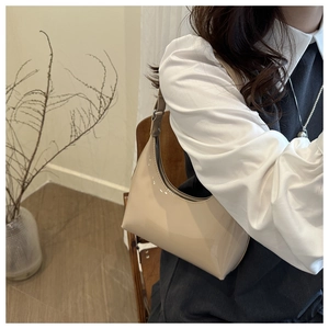 Close-up of minimalist cream glossy hobo bag with sleek black zipper and leather strap