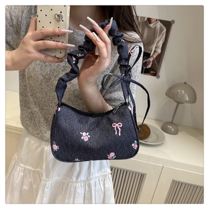 Close-up of sweet bow embroidery on blue denim shoulder bag with scrunchie handle