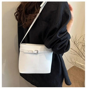 Dettaglio di una borsa a secchiello bianca con trama in pelle martellata e fibbia