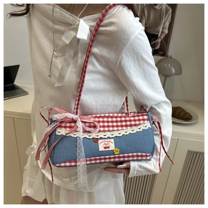 Detailed close-up of lace trim and red plaid edges on a denim shoulder bag with cherry tag
