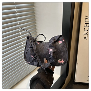 Detail of blue denim mini bag with pink floral rose patterns and ruffled cloud handle