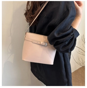 Detail of light apricot bucket bag featuring pebbled texture and metal buckle strap