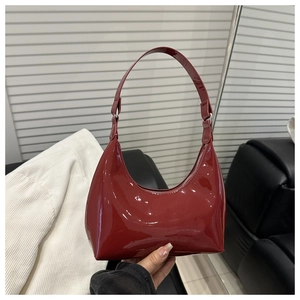 Detail of glossy deep red patent leather shoulder bag with metallic buckle highlights