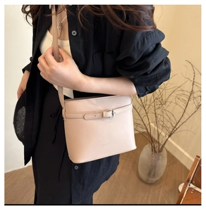 Dettaglio borsa a secchiello beige con trama litchi, fibbia in argento e tracolla sottile
