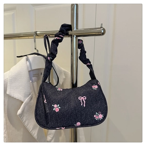 Detail of denim bow print handbag with pleated cloud handle on a display stand