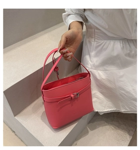Dettaglio della borsa a secchiello rosa brillante con trama litchi e chiusura in metallo