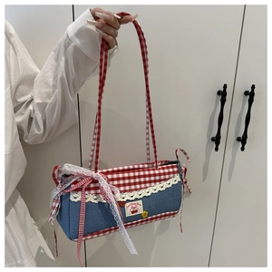 Detail of blue denim bag with red checkered fabric, lace trim, and cherry ribbon bows