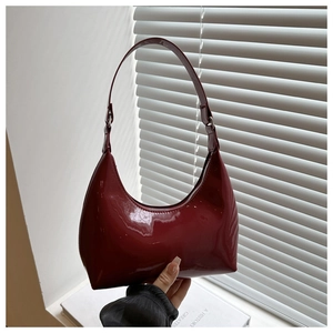 Close-up of deep wine red patent leather underarm bag with glossy finish and silver buckle