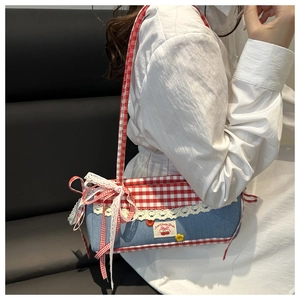 Detail of sweet cherry patch with white lace trim on blue denim shoulder bag