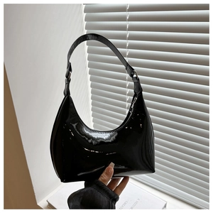 Detail shot of the glossy black patent leather finish on the minimalist shoulder bag