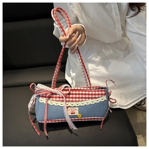 Detail of denim bag featuring lace trim, red gingham patterns, and cherry embroidery