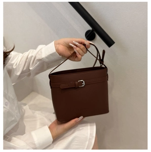Dettaglio di una borsa a secchiello vintage in pelle marrone scuro con fibbia regolabile