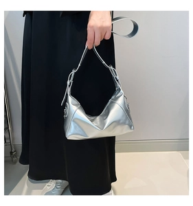 Close-up of silver mirror leather surface and metal buckle on the crescent shoulder bag