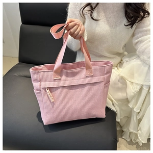 Pink woven tote bag featuring vertical texture, side pocket and tassel charm detail
