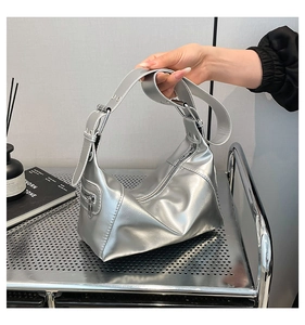 Detail of silver metallic underarm bag showing mirror finish and side zipper pocket