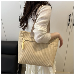 Detail of beige woven tote bag with vertical stripes and yellow zipper pull detail